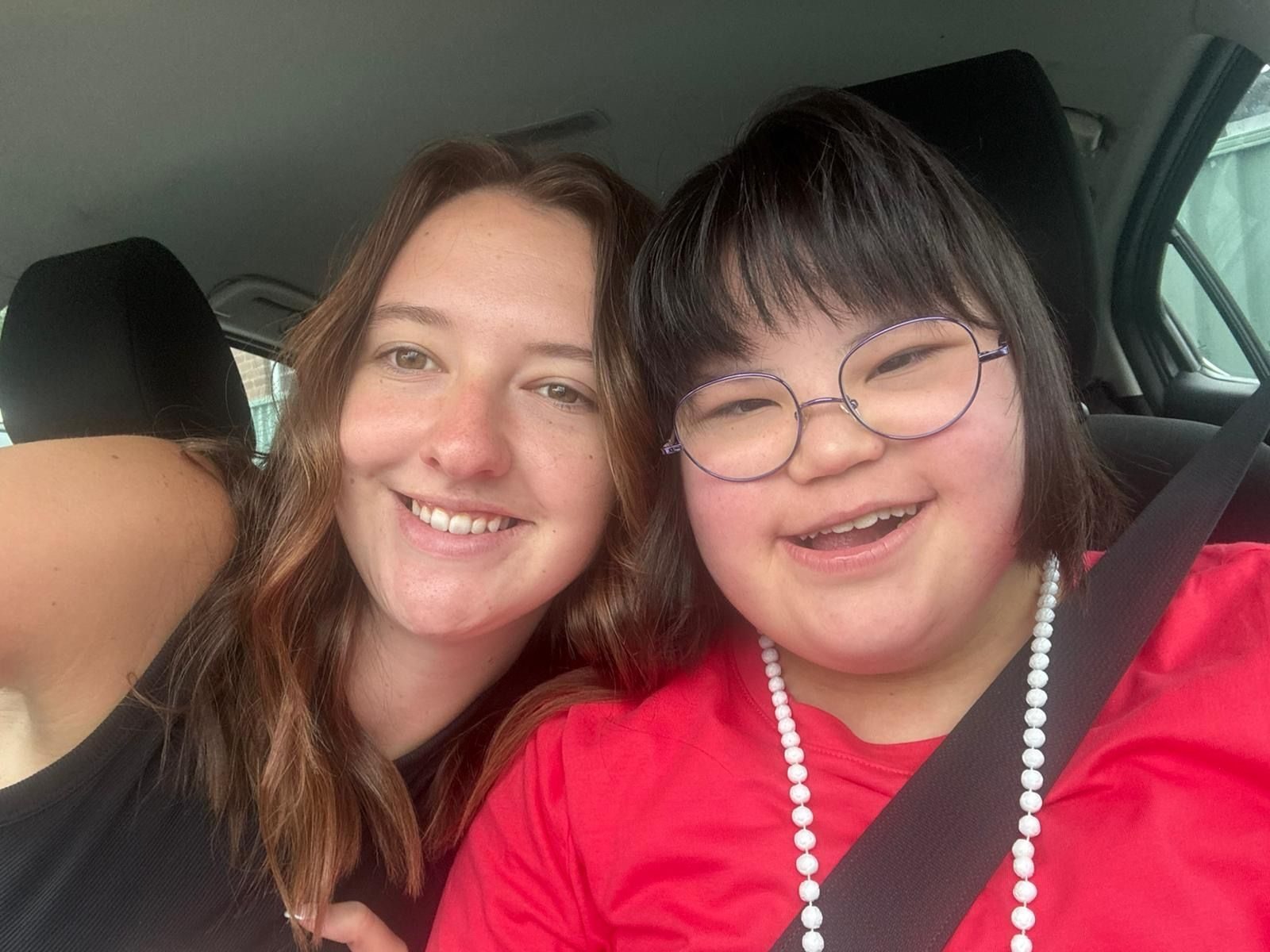 A Morhaven support worker and a member smiling together in the car on the way to an activity.